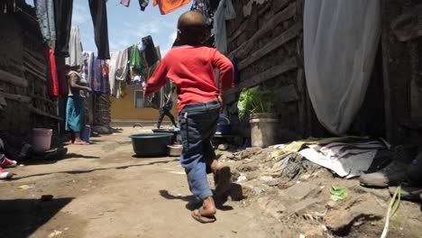 Niños-Africanos-Jóvenes-Jugando-Corriendo-Caminando-Por-Los-Barrios-Marginales-De-Un-Pueblo-Pobre-Mientras-Pasaban-A-La-Madre-Lavando-La-Ropa---Siguiendo-El-Tiro-De-Seguimiento-180fps-En-Cámara-Lenta