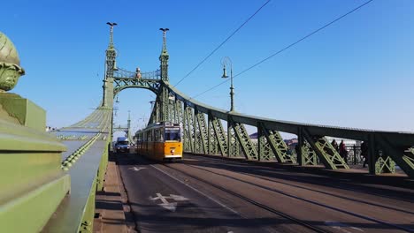 Gelbe-Straßenbahn-Fährt-Tagsüber-Auf-Der-Freiheitsbrücke-In-Budapest,-Ungarn-–-Mittlere-Aufnahme