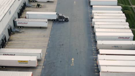 Aerial-dolly-shot,-trailers-lined-up-at-dock-of-distribution-center-load-and-unload,-e-commerce,-freight,-shipping,-logistics-theme
