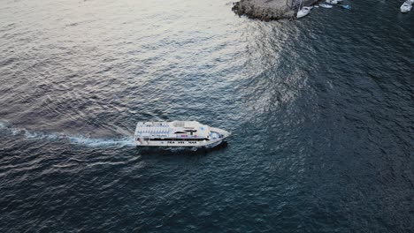 Aerial-View-of-Touristic-Boat-Sailing-by-the-Coast-of-Amalfi-City,-Mediterranean-Sea,-Italy