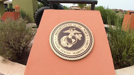 Pull-back-from-the-Marine-Corps-bronze-emblem-to-reveal-155mm-Howitzer-cannon-at-the-Veteran's-Memorial,-Fountain-Park,-Fountain-Hills,-Arizona
