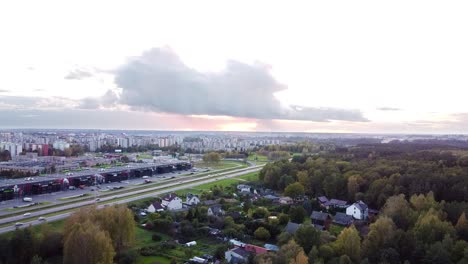 Luftaufnahme-Der-Stadt-Kaunas-In-Der-Ferne-Mit-Einem-Schönen-Kleinen-Dorf-In-Der-Nähe-Und-Einer-Autobahn-Dazwischen