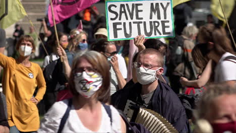 Aufstand-Gegen-Den-Klimawandel-Demonstranten,-Die-Aufgrund-Der-Coronavirus-Pandemie-Schutzmasken-Tragen,-Tanzen-Vor-Jemandem,-Der-Ein-Plakat-Mit-Der-Aufschrift-„Rettet-Meine-Zukunft“-Hochhält.