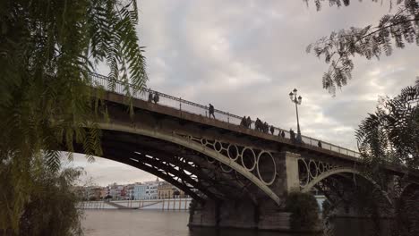 Menschen-Gehen-über-Die-Berühmte-Triana-Brücke,-Sevilla,-Spanien,-Bewölkter-Abendhimmel