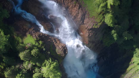 AERIAL-LOWERING-ROTATING-to-a-dramatic-waterfall-in-Switzerland,-Iffigfall