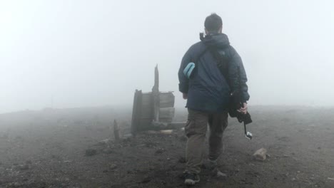 Man-walks-on-top-of-Mount-Asahidake-in-Japan-while-it-rains-and-misty-weather