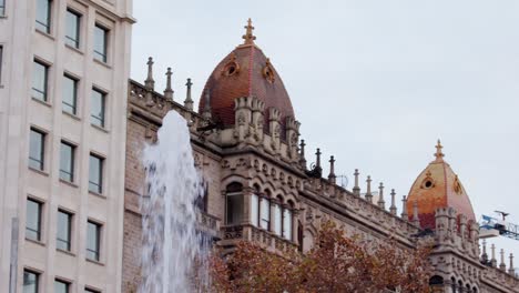 Water-stream-in-front-of-Gothic-inspired-building-with-orange-tile-domes