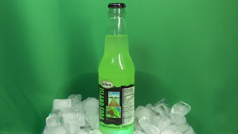 1-3-Botella-De-Vidrio-De-Bebida-De-Pomelo-Con-Sabor-A-Marca-Grace-Que-Gira-360-Grados-En-Un-Recipiente-Lleno-De-Hielo-Frente-A-Una-Pantalla-Verde