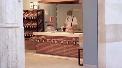 Man-Wearing-Face-Mask-Packing-And-Weighing-Food-In-A-Store-In-Malaga,-Spain---wide-shot