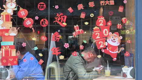 Kunden-Essen-In-Einem-Restaurant,-Das-Vor-Dem-Bevorstehenden-Chinesischen-Neujahrsfest-Mit-Zahlreichen-Aufklebern-Zum-Thema-„Chinesisches-Neujahr“-Geschmückt-Ist