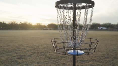 Made-Disc-Golf-Putt-in-the-Morning-Light-of-a-beautiful-Sunrise-|-Disc-Golfer-then-retrieves-Frisbee-from-Cage-of-Disc-Golf-Basket