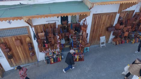 Tangier-souvenir-shops-in-the-Medina,-People-walking-down-the-street,-Pan-shot