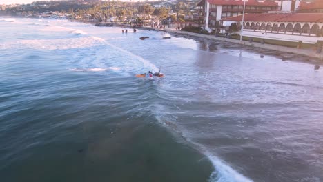 kayak-fisherman-launches-through-the-surf-in-La-Jolla,-aerial-view