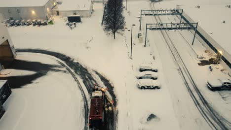 Drone-shot-truck-with-snowplough-driving-in-heavy-winter-storm-in-USA