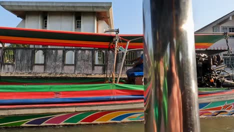 POV-Fahrt-Auf-Einem-Longtail-Boot-Mit-Einem-Anderen,-Der-Auf-Den-Wasserstraßen-Des-Khlong-Bangkok-Yai-Canal-Vorbeifährt,-Mit-Hoher-Sonne-Am-Himmel