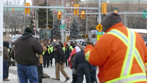 Police-force-patrol-walking-towards-freedom-convoy-protesters-demonstration-in-Windsor,-Ontario-Canada