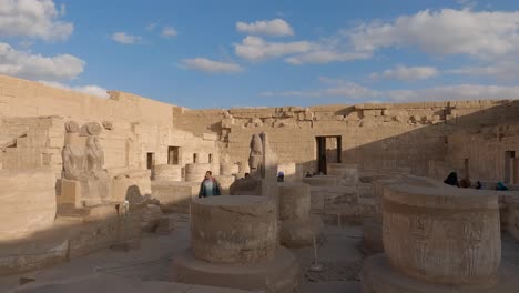 Hypostyle-Hall-in-Medinet-Habu-temple,-tourists-at-archaeological-site,-remains-of-columns