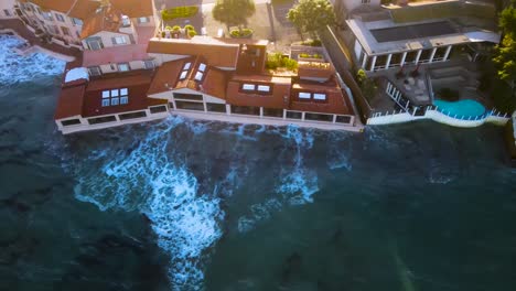 Aerial-view-of-waterfront-restaurant-getting-hit-by-waves