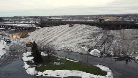 Aerial-footage-captures-the-cleanup-after-a-deadly-storm-in-Buffalo,-New-York,-as-snow-is-gathered-in-a-big-pile,-showcasing-the-resilience-and-strength-of-the-community