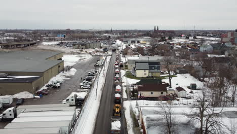 Aerial-footage-of-a-line-of-snow-filled-trucks-ready-to-dump-it-on-a-massive-pile,-depicting-the-snow-clearing-efforts-after-a-heavy-winter-storm