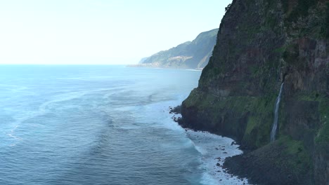 Landscape-shot-of-a-cliff-in-the-Northern-Coast-of-Madeira,-Portugal-with-a-waterfall-coming-from-it