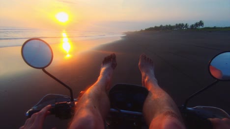 Motorrad-Pov-Fahren-Mit-Erhobenen-Beinen-Am-Strand-Bei-Sonnenuntergang,-Lustiger-Stunt