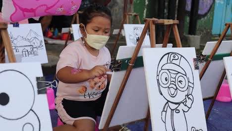 Indonesia---Jan-15,-2023-:-Asian-little-girl-coloring-a-picture-on-the-street
