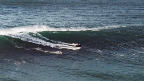 Ein-Surfer-An-Einem-Seil-Hinter-Einem-Jetski-Wird-Auf-Eine-Riesige-Welle-Gezogen,-Auf-Der-Er-Reitet
