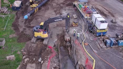 Machines-working-at-water-main-pipe-installation-site,-aerial-parallax