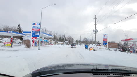 POV-driving-on-an-icy-road,-passing-gas-stations,-highlighting-the-hazards-and-challenges-of-winter-driving