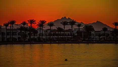 Amanecer-Junto-Al-Hotel-Frente-A-La-Playa-En-Hurghada,-Egipto-Con-Palmeras-Y-Montaña-En-Silueta