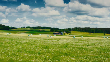 A-truck-driving-down-a-scenic-road-surrounded-by-lush-green-meadows-and-fields-in-this-sideways-moving-drone-footage
