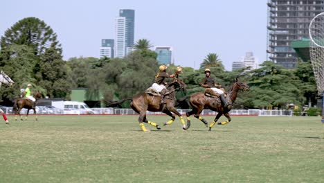 Group-of-people-playing-traditional-sport,-riding-on-horseback,-throwing-and-passing-the-ball-across-to-his-team-mates-during-pato-horseball-match-at-Campo-Argentino-de-Polo,-Buenos-Aires,-Argentina