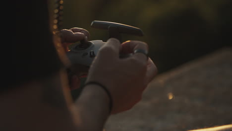 Close-up-of-male-hands-using-controller-for-DJI-FPV-drone,-golden-hour
