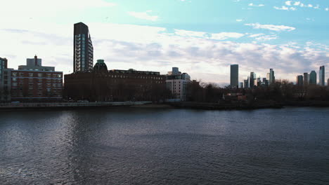 Aerial-view-passing-a-ferry-on-the-East-river,-in-sunny-Manhattan,-New-York,-USA