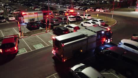 Firefighters-trucks-on-a-car-parking-lot,-with-siren-lights-on,-at-night