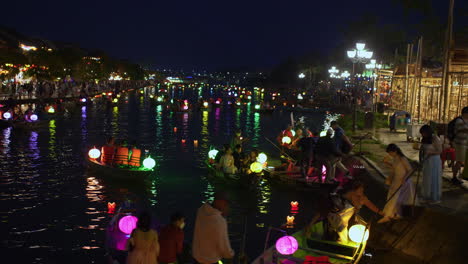 Tourist-taking-lantern-boat-ride-on-Hoai-river-in-Sampan-boats-in-ancient-town-of-Hoi-An-during-light-festival-at-night,-Vietnam
