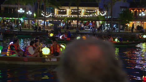 Tourist-taking-lantern-boat-ride-on-Hoai-river-in-Sampan-boats-in-ancient-town-of-Hoi-An-during-light-festival-at-night,-Vietnam