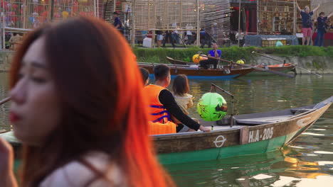 Tourist-taking-lantern-boat-ride-on-Hoai-river-in-Sampan-boat-in-ancient-town-of-Hoi-An-at-evening,-Vietnam