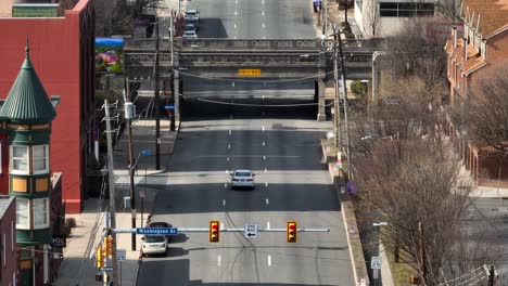 Long-aerial-zoom-of-car-driving-in-city-street-of-Harrisburg,-Pennsylvania-in-winter