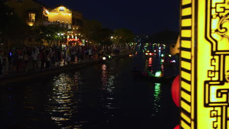 Tourist-taking-lantern-boat-ride-on-Hoai-river-in-Sampan-boats-in-ancient-town-of-Hoi-An-during-light-festival-at-night,-Vietnam