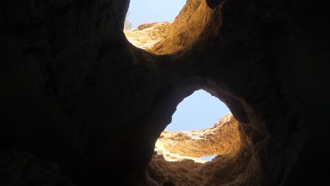 A-sea-cave-in-Algarve,-Portugal-that-looks-like-a-pair-of-eyes-opening-out-to-the-sky