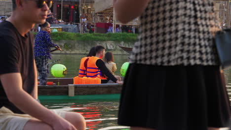 Tourist-taking-lantern-boat-ride-on-Hoai-river-in-Sampan-boat-in-ancient-town-of-Hoi-An-at-evening,-Vietnam