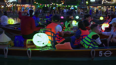 Tourists-taking-lantern-boat-ride-tour-on-Hoai-River-in-Sampan-boats-in-ancient-town-of-Hoi-An-during-light-festival,-Vietnam