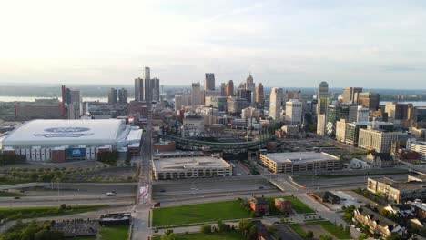 Ascending-shot-of-a-magnificent-urban-skyline-with-a-green-park,-Downtown-Detroit,-Ford-indoor-football-field
