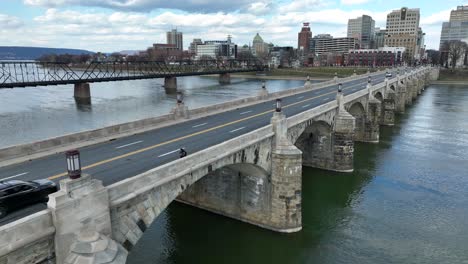 Aerial-rising-shot-of-person-walking-on-bridge-in-front-of-Harrisburg-capital-city