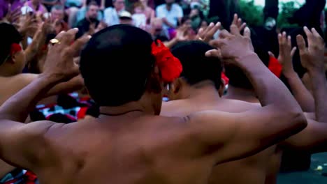 Shot-of-Group-of-shirtless-males-with-flowers-performing-the-Balinese-cultural-fire-dance-at-Uluwatu-temple-and-moving-hands-in-Indonesia,-Bali