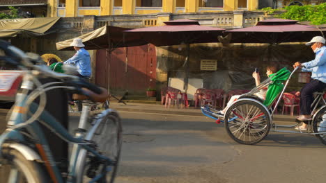 Eine-Dynamische-Aufnahme-Von-Touristen,-Die-Mit-Einem-Fahrradverleih-Durch-Die-Stadt-Hoi-An-In-Vietnam-Streifen