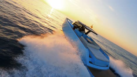 FPV-aerial-following-a-luxury-yacht-as-it-sails-into-a-scenic-sunset-in-Ibiza,-Spain