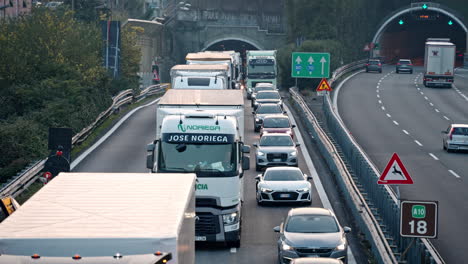 Establisher-view-of-cars-and-trucks-driving-slowly-on-road-under-repair,-Italy